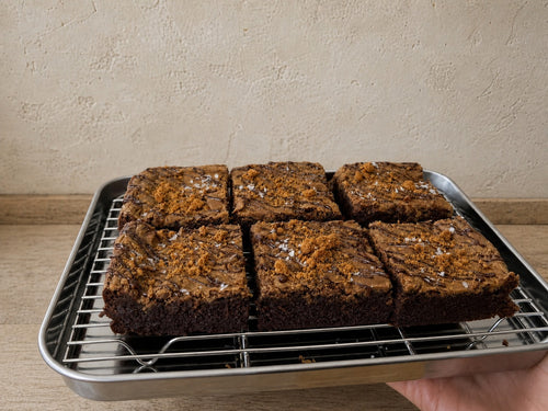 Six Miso Biscoff brownies arranged on a stainless-steel tray.